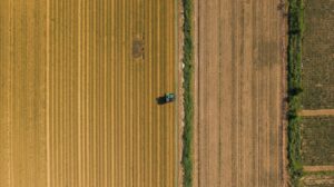 drone surveying agricultural fields in rural greece, tractor below, patterns of rows visible, aerial‑top‑down view, sharp detail, landscape orientation.